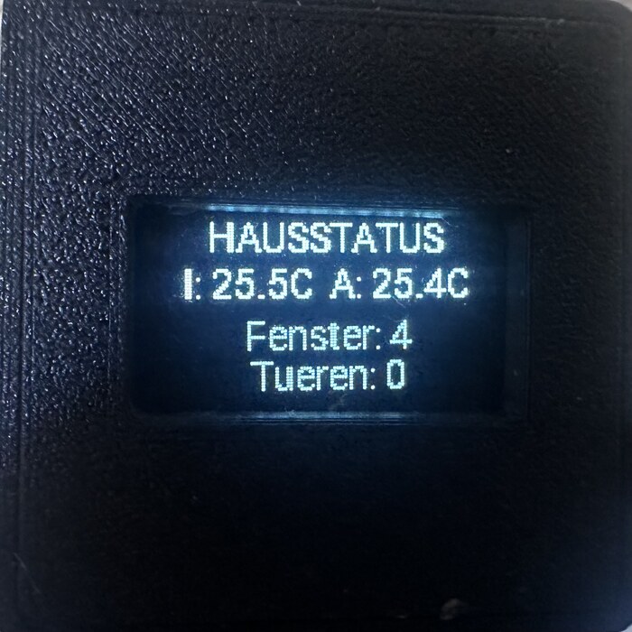 OLED-Display zeigt Hausstatus mit Innen- und Außentemperatur sowie Anzahl offener Fenster und Türen