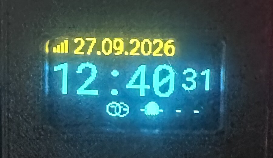 OLED-Display der Kinderzimmer-Uhr mit WLAN-Signalstärke, Datum, Uhrzeit mit Sekunden und kleiner Animations-Icon-Leiste