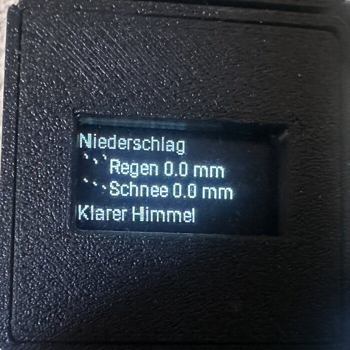 OLED-Display zeigt Niederschlag: 0,0 mm Regen, 0,0 mm Schnee, klarer Himmel